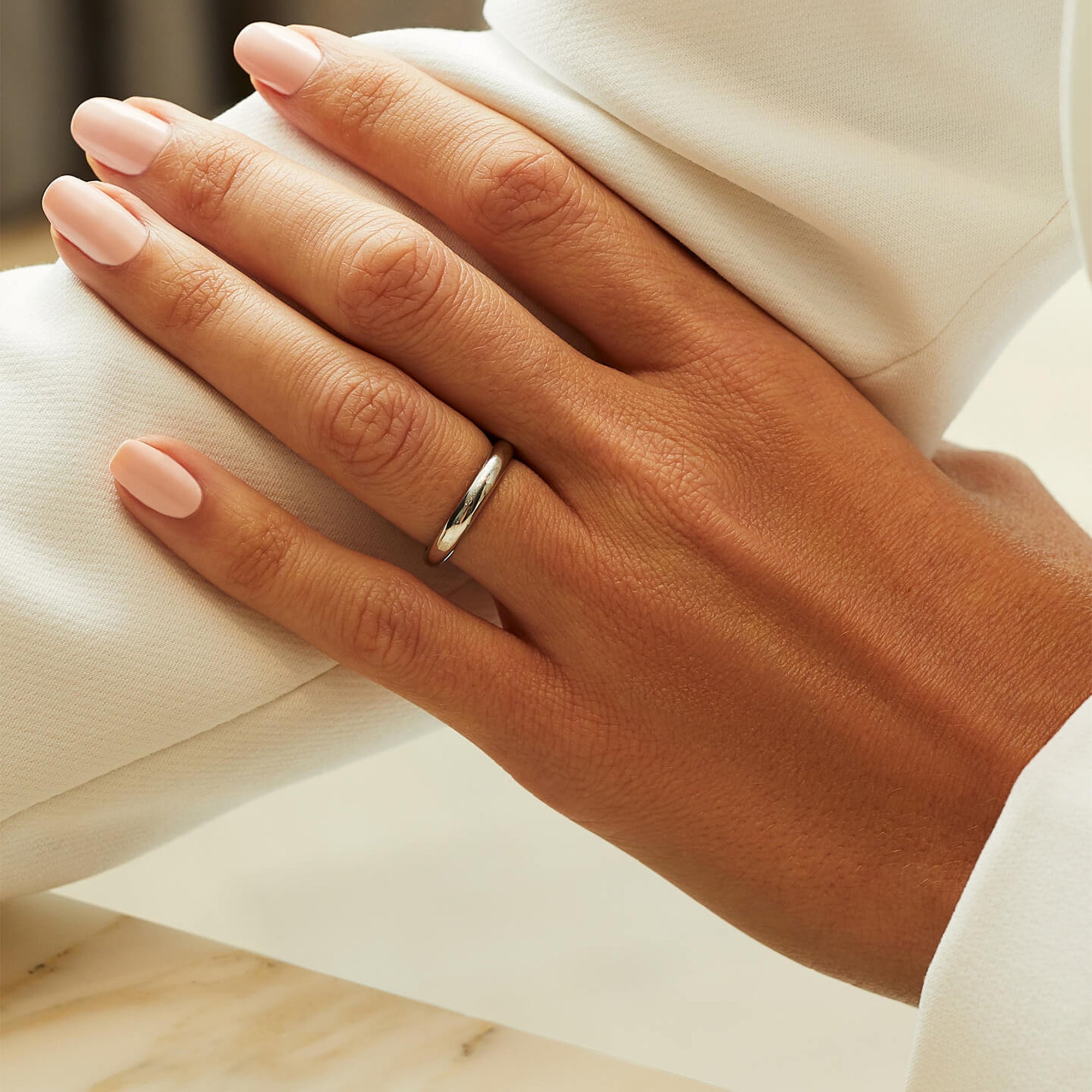 Classic 2.5mm platinum court-shaped wedding band modeled on a woman's finger.