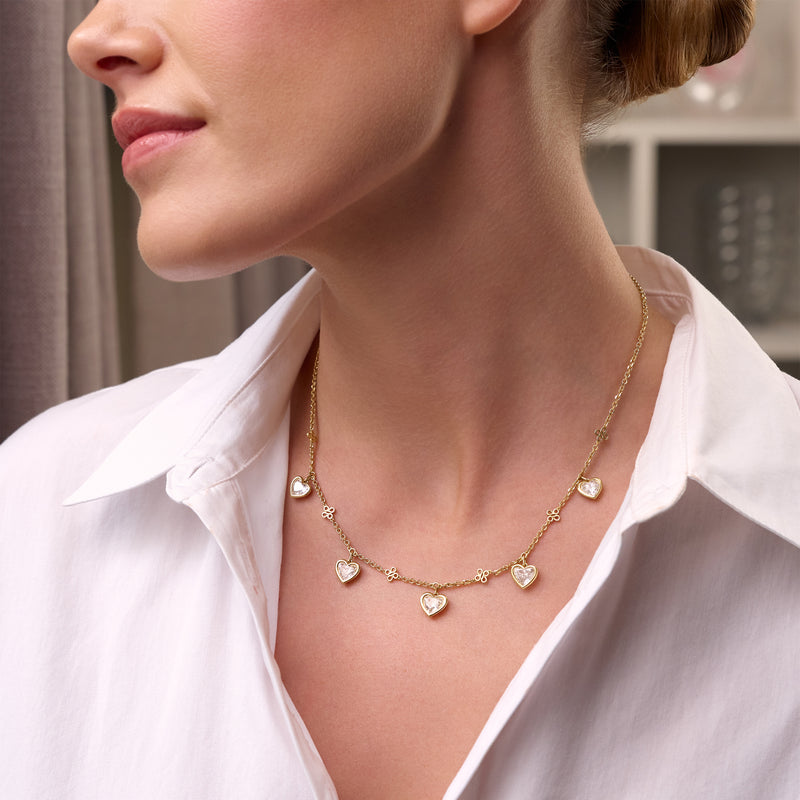 Beach Heart Diamond Yellow Gold Necklace with five heart-shaped diamonds worn by a model.