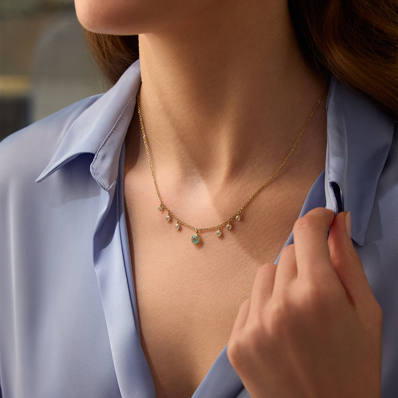 Beach Paraiba tourmaline and diamond 18 carat yellow gold necklace worn by a woman.