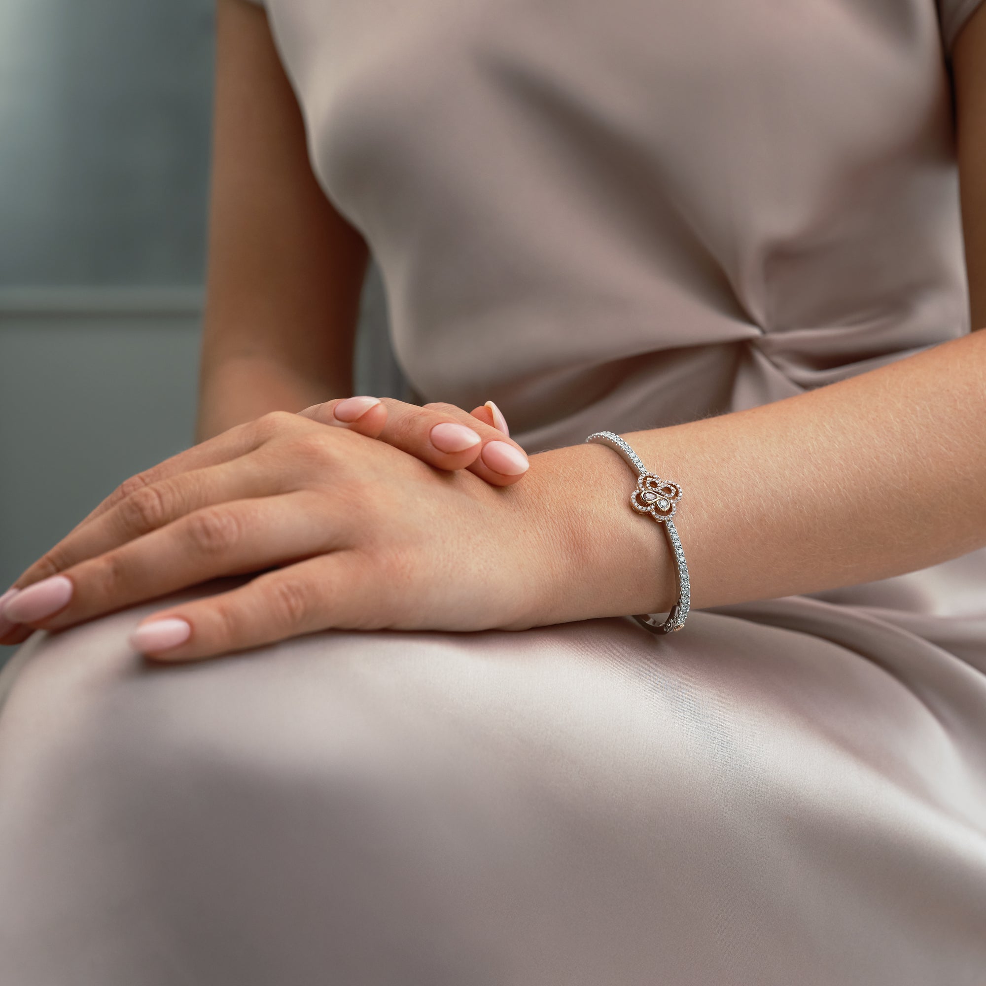 Be Boodles pink and white diamond bangle in platinum and rose gold worn by a woman.