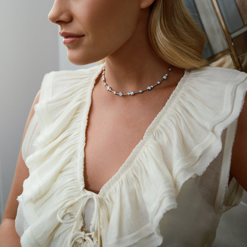 Raindance platinum diamond necklace worn by a woman in a white ruffled top.