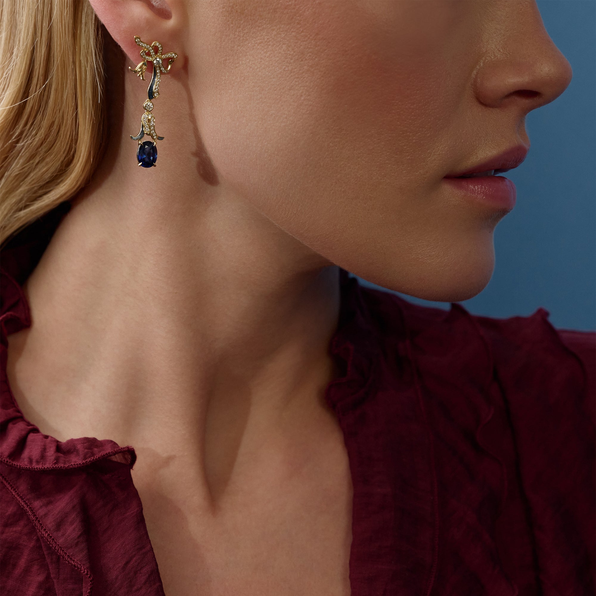 The Palace Collection Presence Chamber yellow gold drop earring with diamonds and an oval sapphire worn by a model.