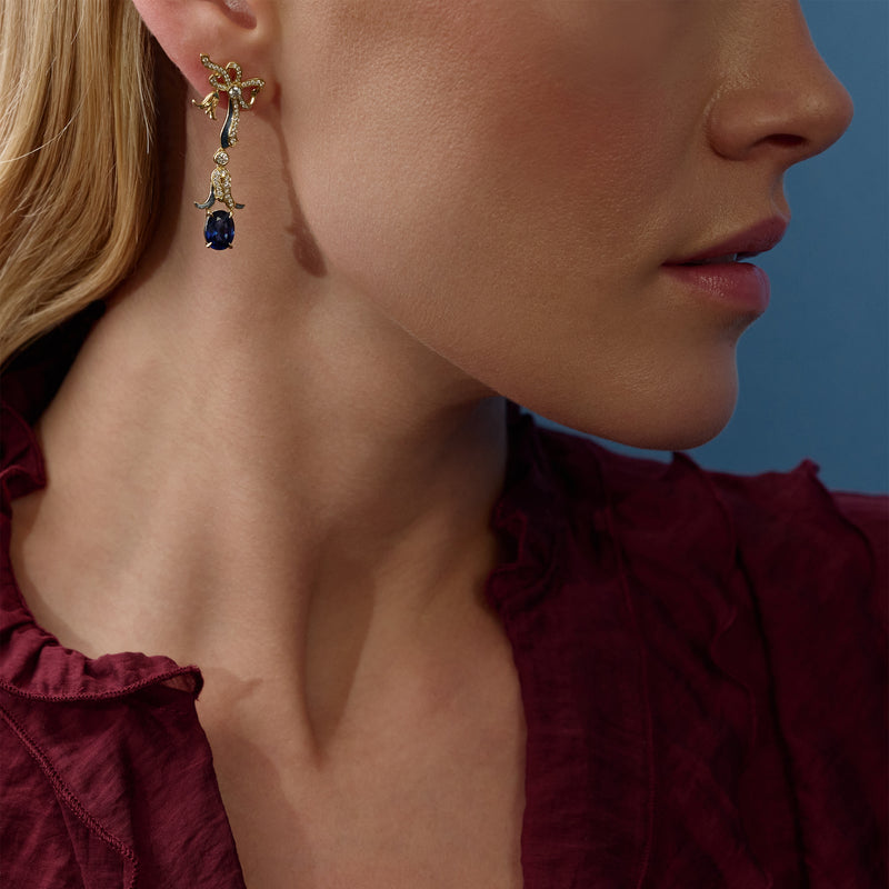 The Palace Collection Presence Chamber yellow gold drop earring with diamonds and an oval sapphire worn by a model.