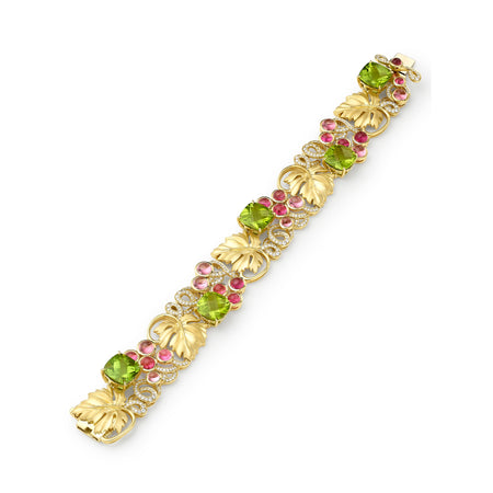 Gold bracelet with green and pink gemstones on a white background