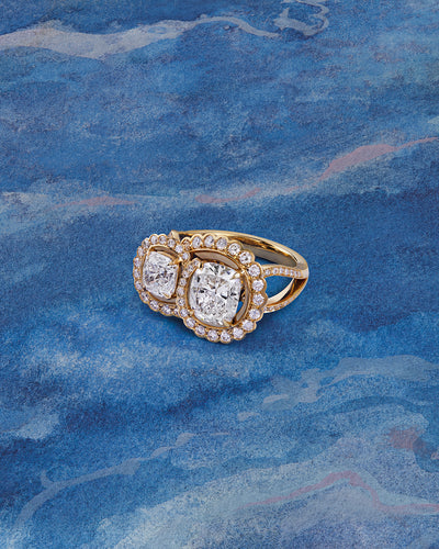 A Monaco design ring set with two cushion cut centre diamonds and brilliant cut diamonds in single mine origin gold, by Boodles.