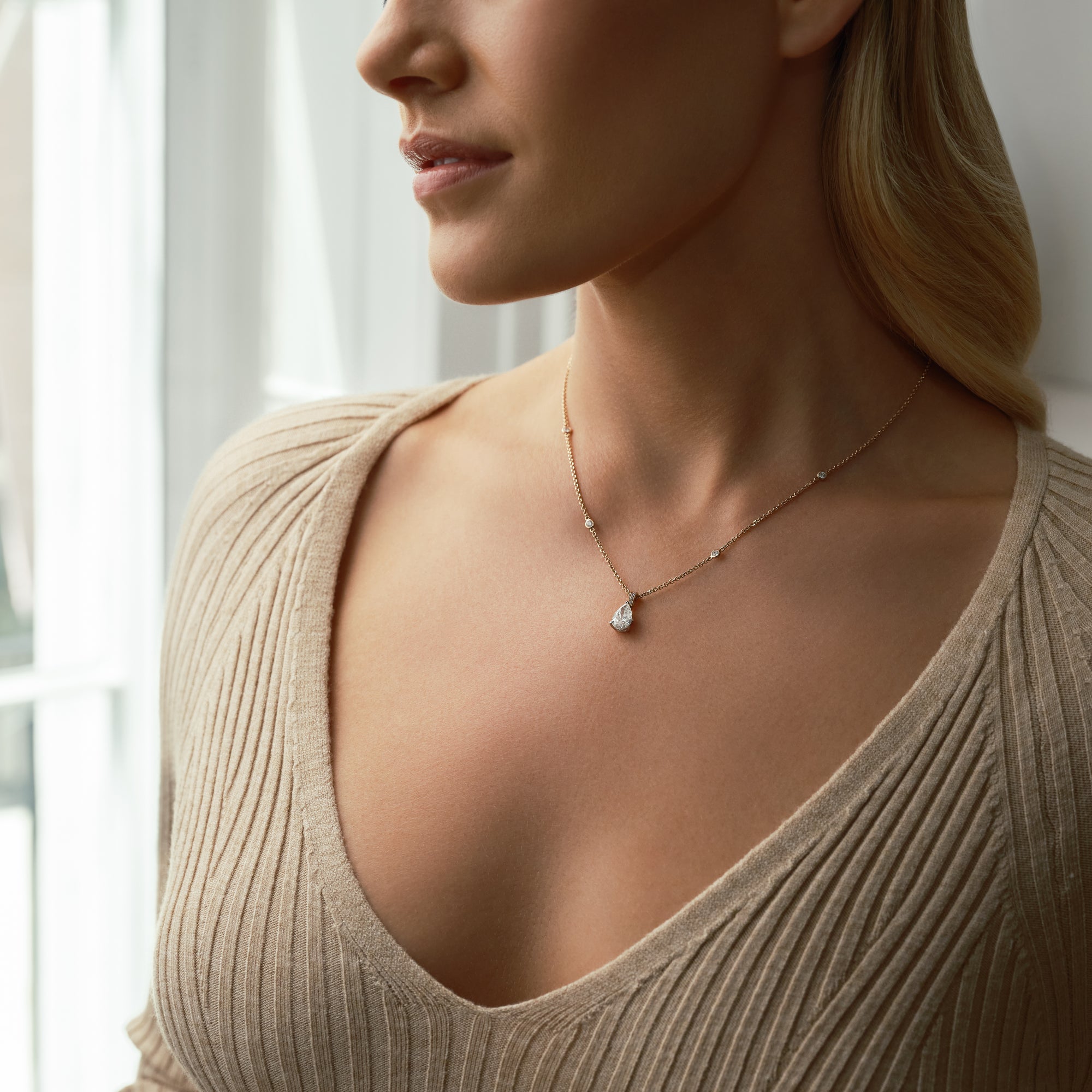 Classic rose gold pear diamond pendant worn by a woman.
