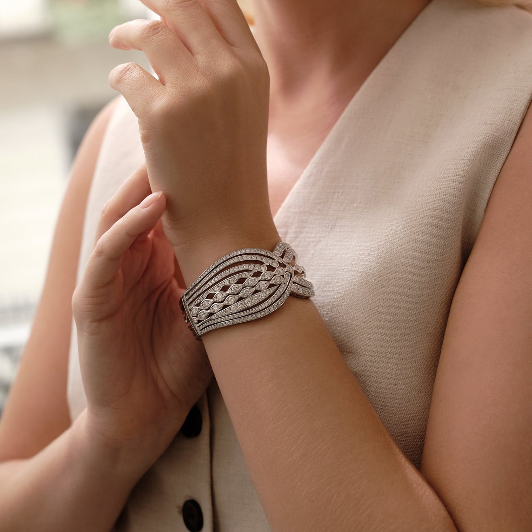 The Tide diamond platinum bangle with an intricate wave design, worn on a woman's wrist.