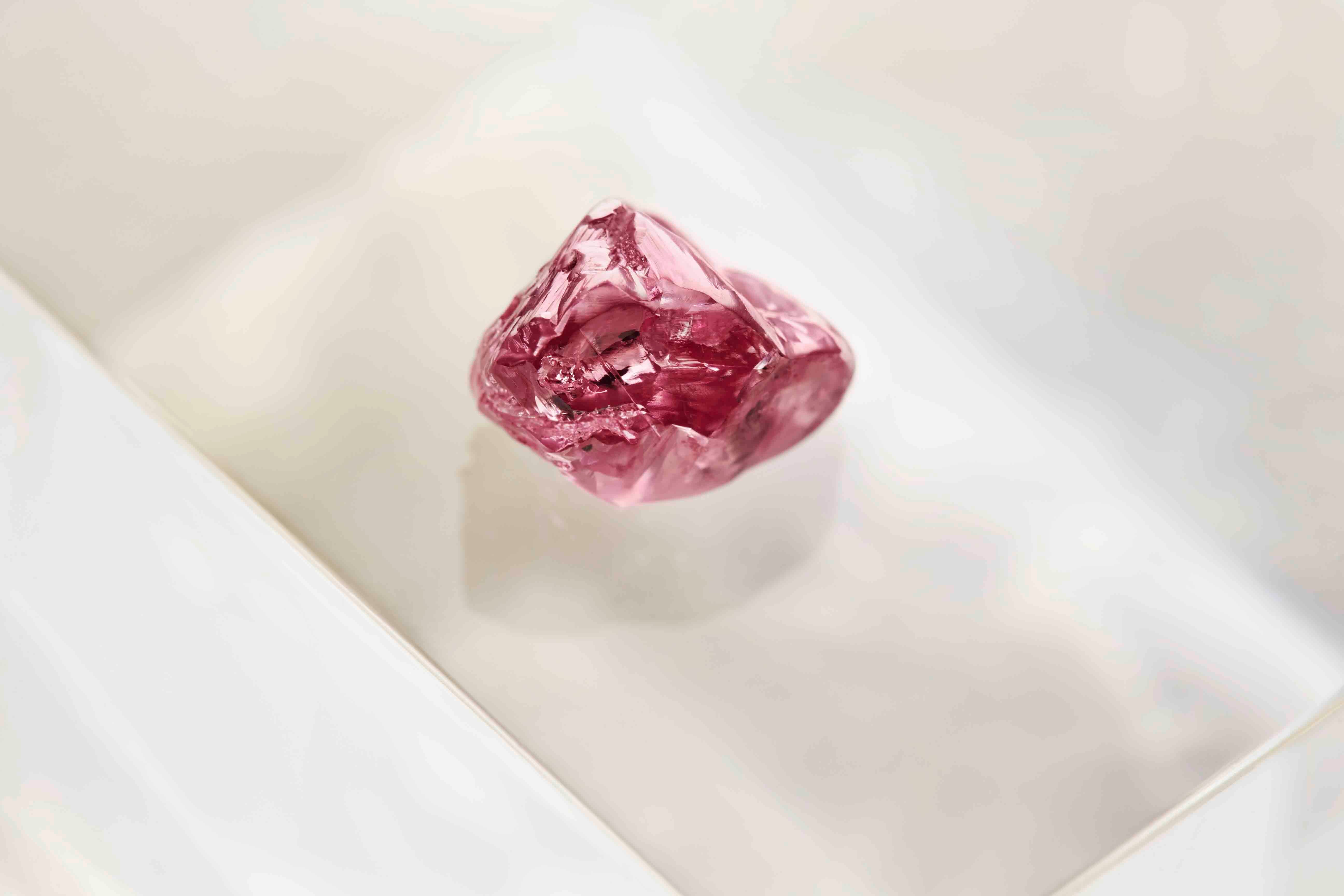 Argyle mine rough pink diamond on a light beige background