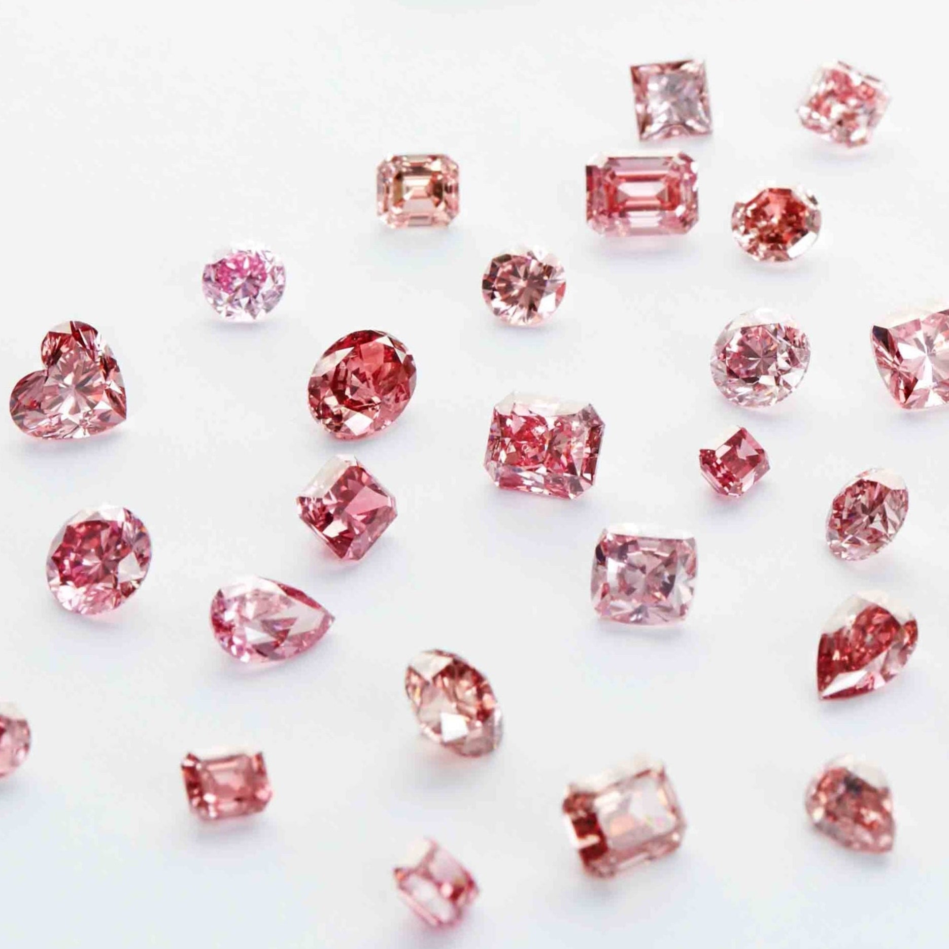 Small pink cut and polished diamonds on a white surface.