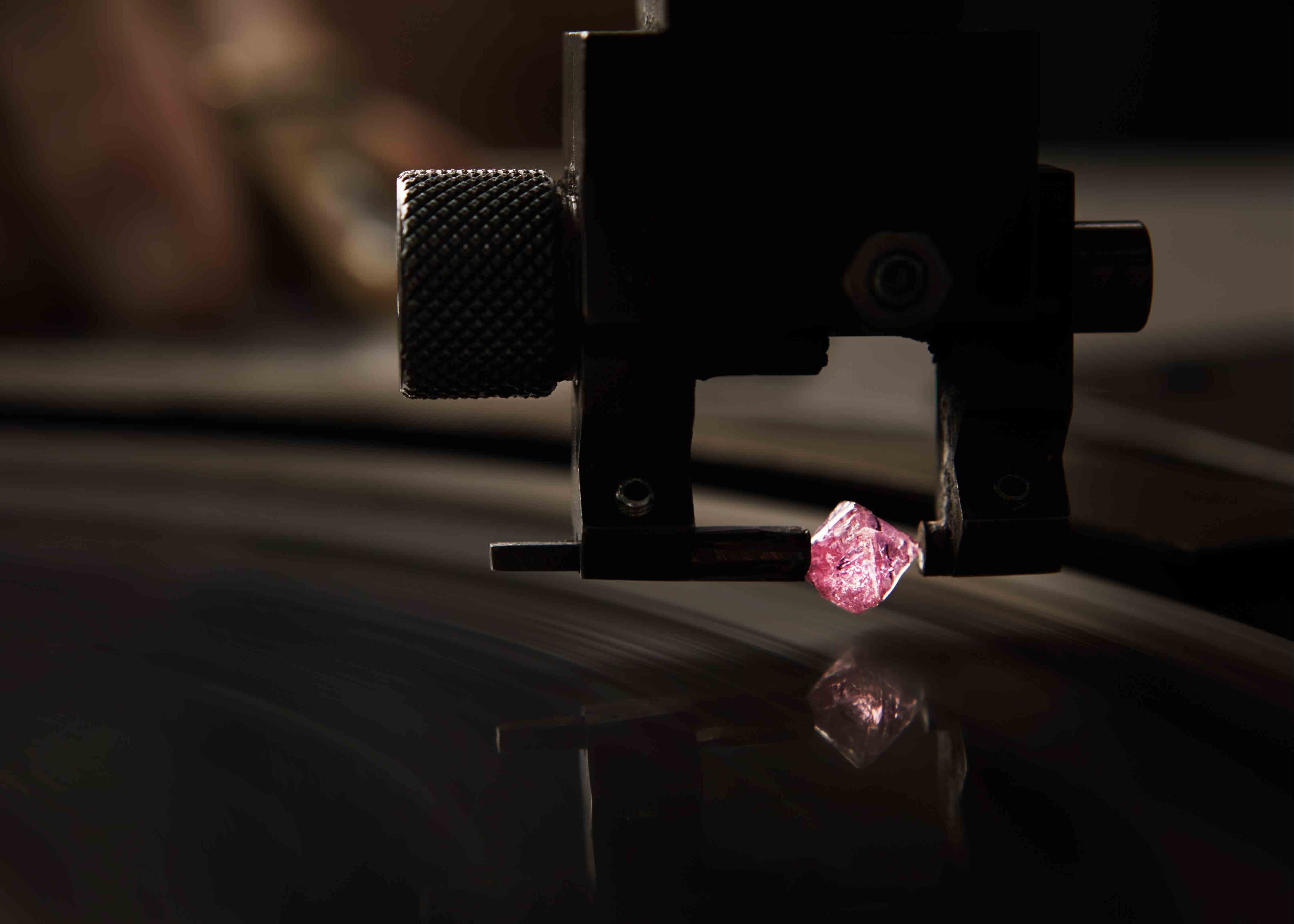 A rare pink Argyle mine diamond being cut in the workshop.