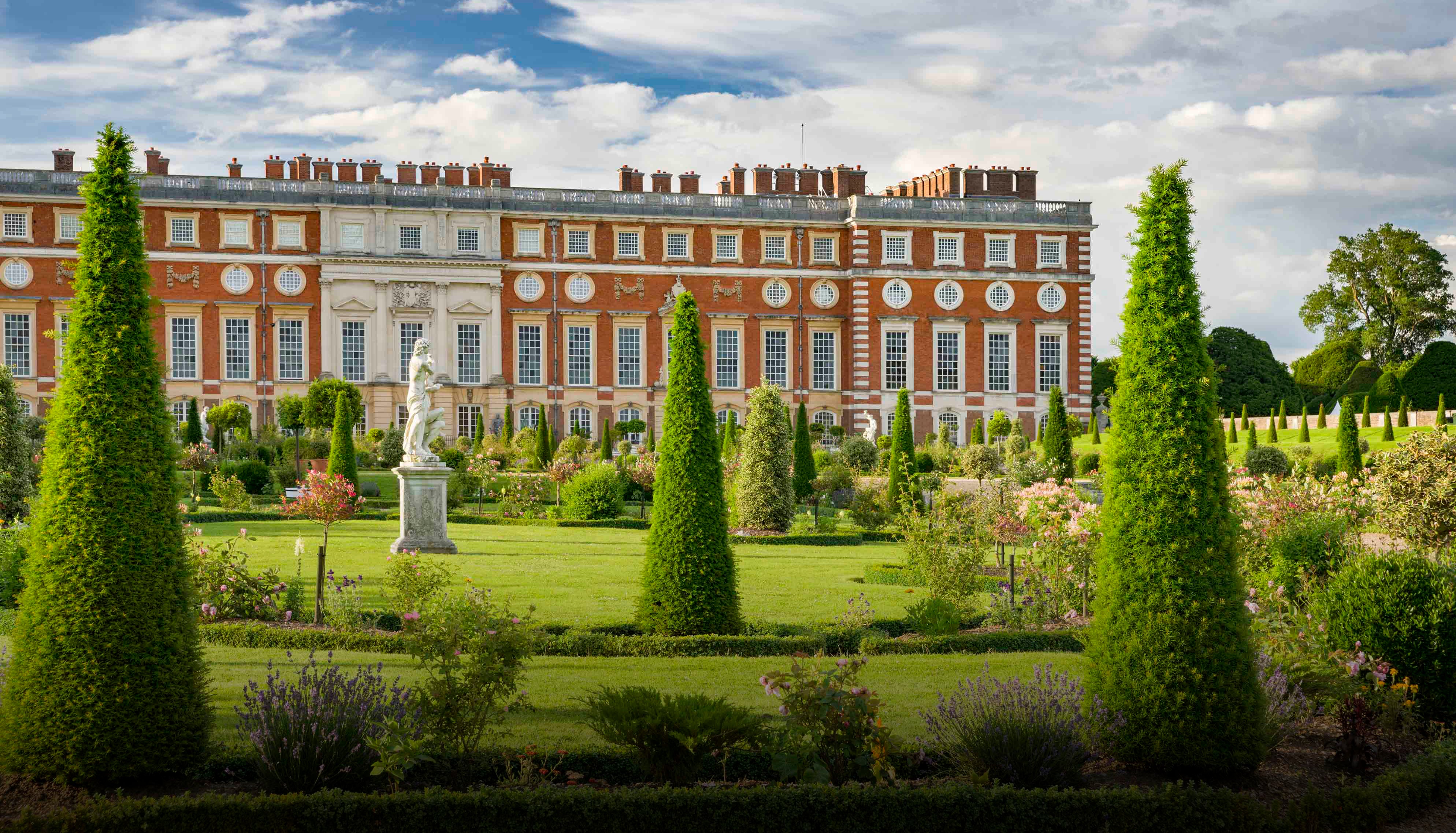 Stately home with formal gardens and a statue in the foreground. Historic Royal Palaces, Chelsea flower show, Boodles garden.