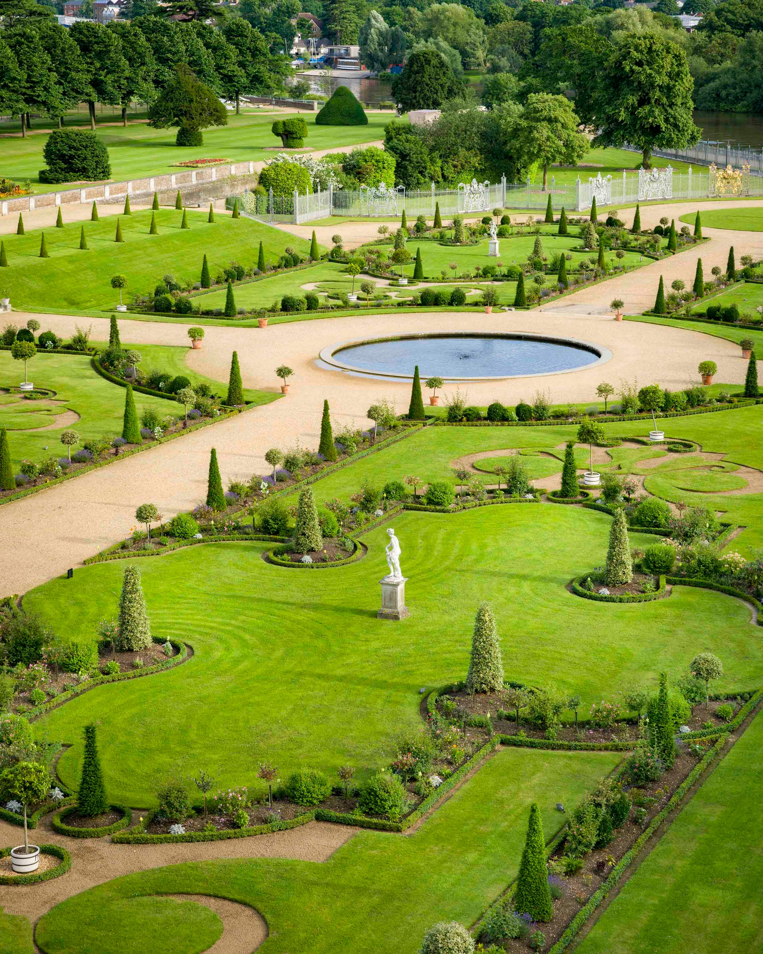 Aerial view of a meticulously landscaped garden with a pond and statues. Historic royal palaces. 