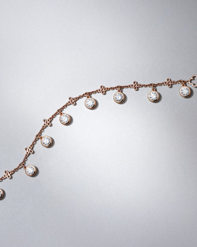 Beach jewellery rose gold necklace with round brilliant diamond charms by Boodles on a light gray background