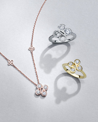 Boodles jewellery collection with two diamond BeBoodles rings and a rose gold necklace on a light grey background