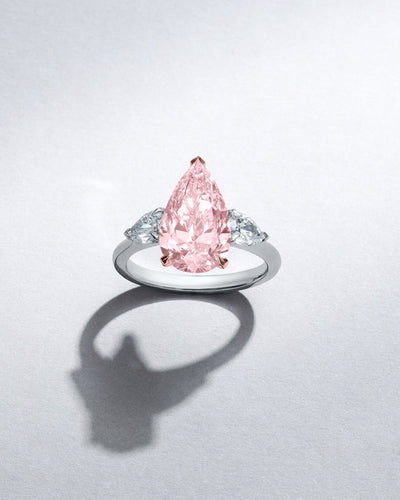 Boodles high jewellery pink diamond pear cut engagement ring with pear cut white diamonds set in a classic trilogy design, on a white background