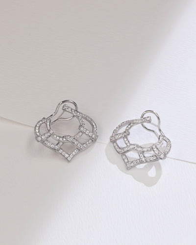 A pair of silver-toned geometric hoop earrings with pavé-set clear stones, displayed on a clean white surface with soft shadows.